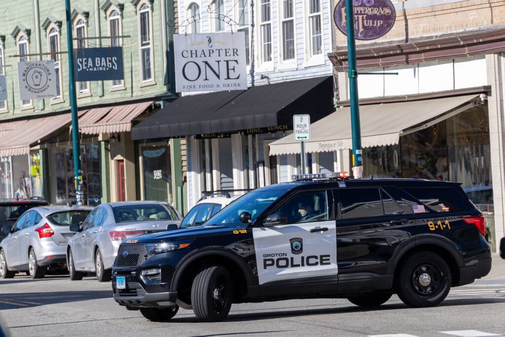 A Groton Town Police Car parked in front of a row of businesses.