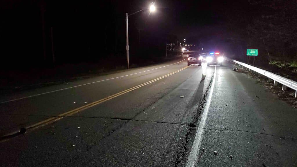 A police car responds to an accident on a Groton road at night.