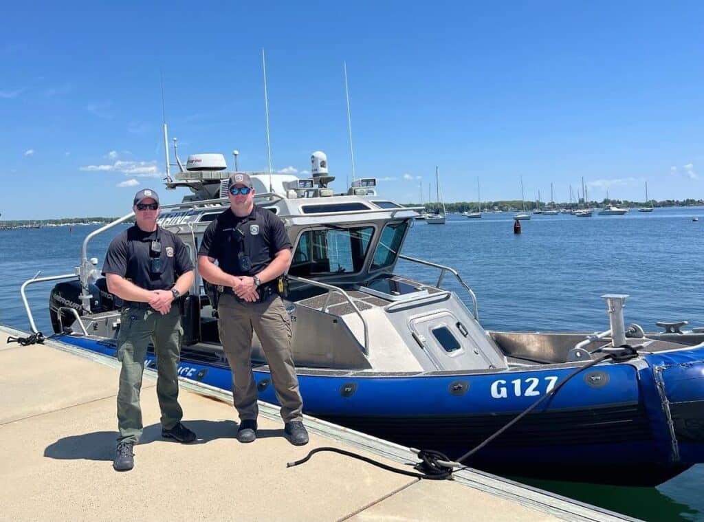 Two Groton Police officers standing in front of a department boat.